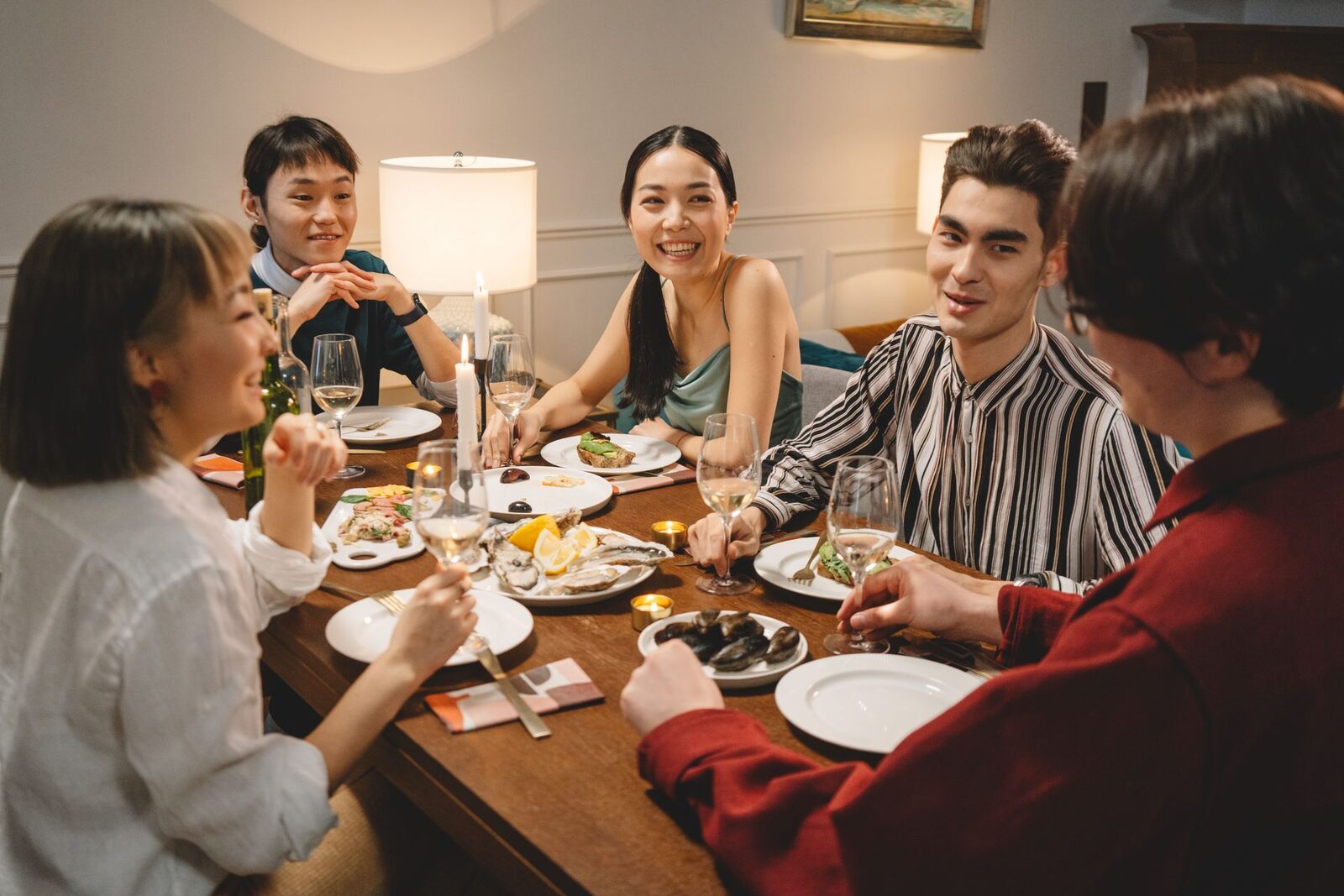 Grupo de amigos riéndose alrededor de una mesa llena de platos