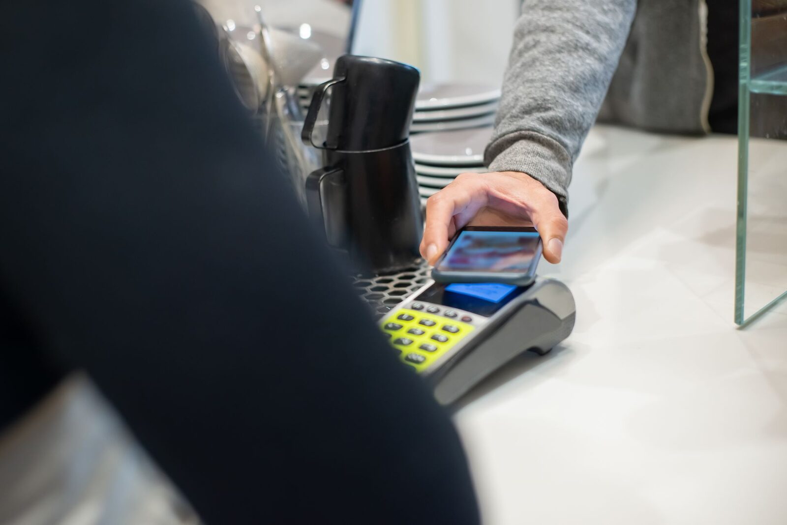 Cliente acercando el móvil a un datáfono en una cafetería